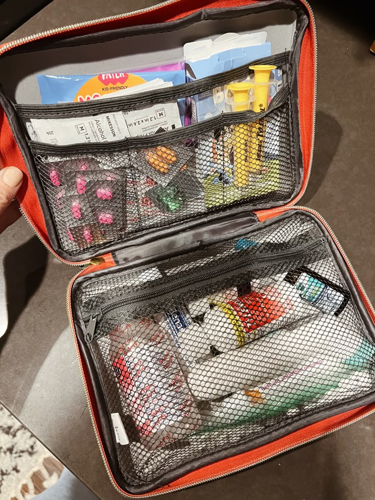 Open first aid kit on a table, filled with medications, bandages, and medical supplies in organized compartments.