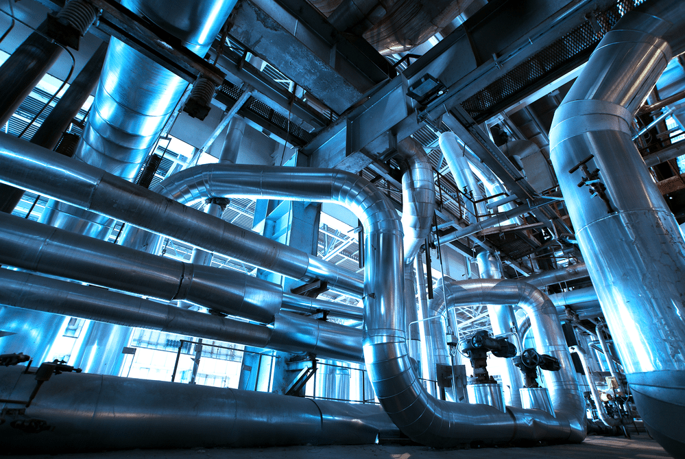Industrial pipes and valves in a factory setting with blue lighting, showcasing a complex engineering network.