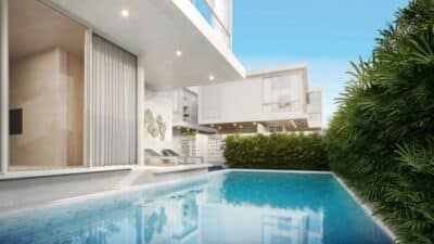 Modern luxury house with a sleek pool, surrounded by lush greenery under a clear blue sky.