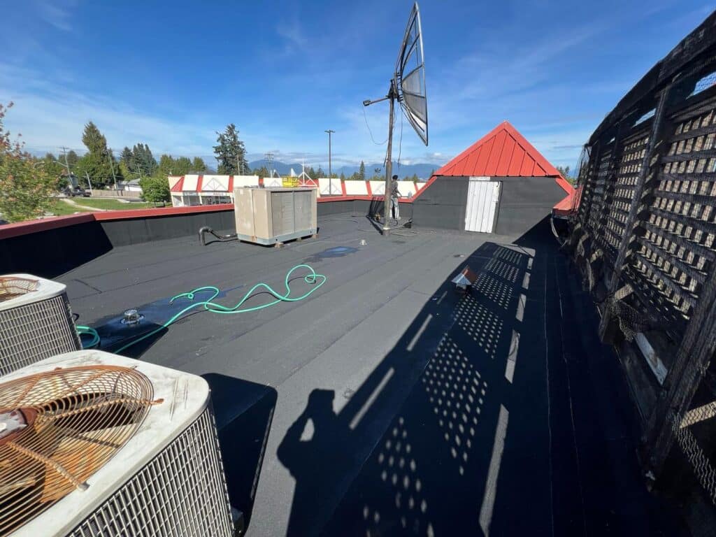Flat rooftop with satellite dish, HVAC units, and blue sky background.