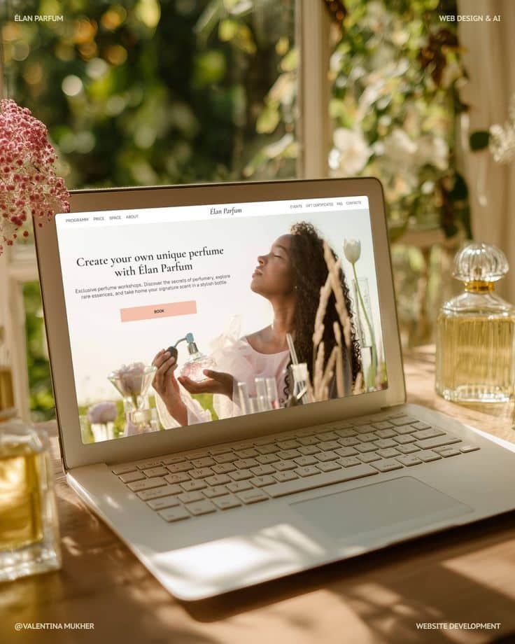 Laptop displaying Elan Parfum website in sunlight amidst perfume bottles and flowers.