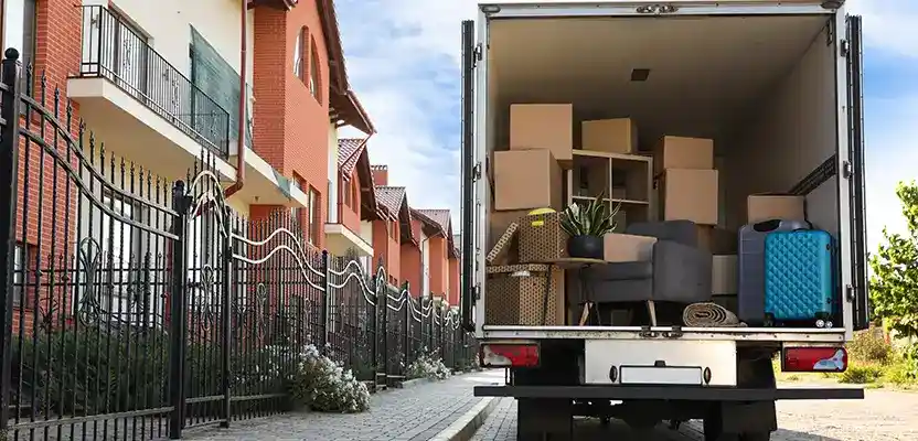 Moving truck filled with boxes and furniture parked on a residential street.