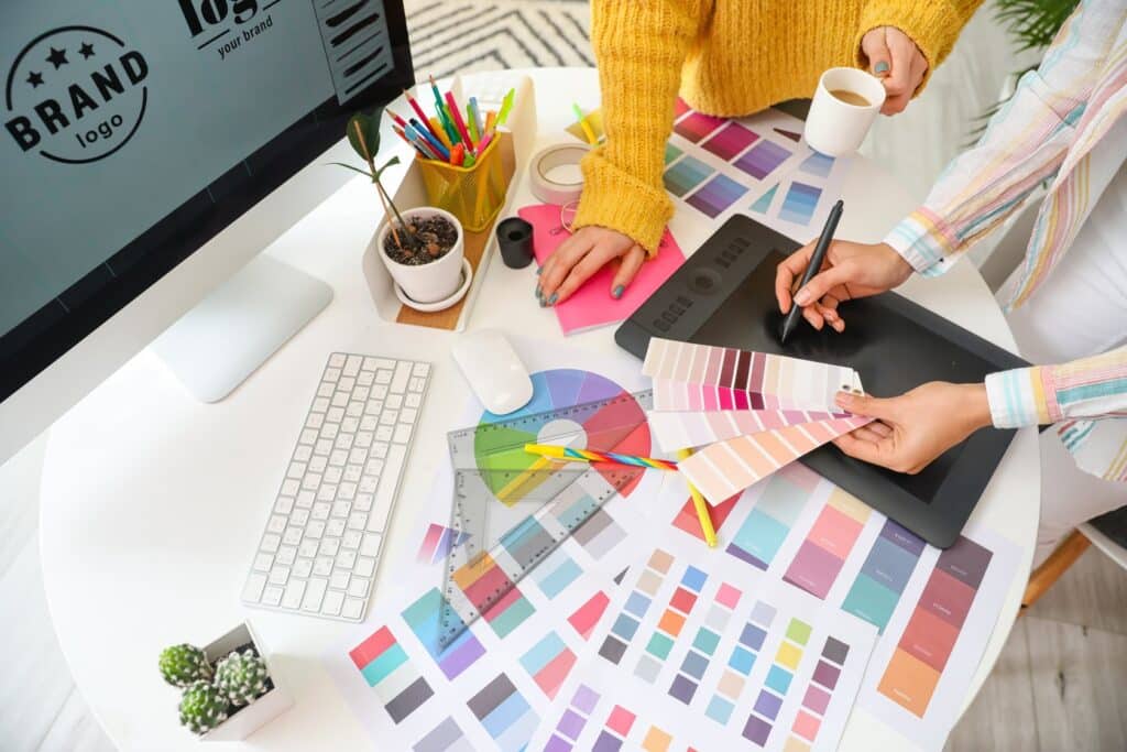 Designers choosing color palettes, working on a branding project with digital tools and printed swatches on a desk.