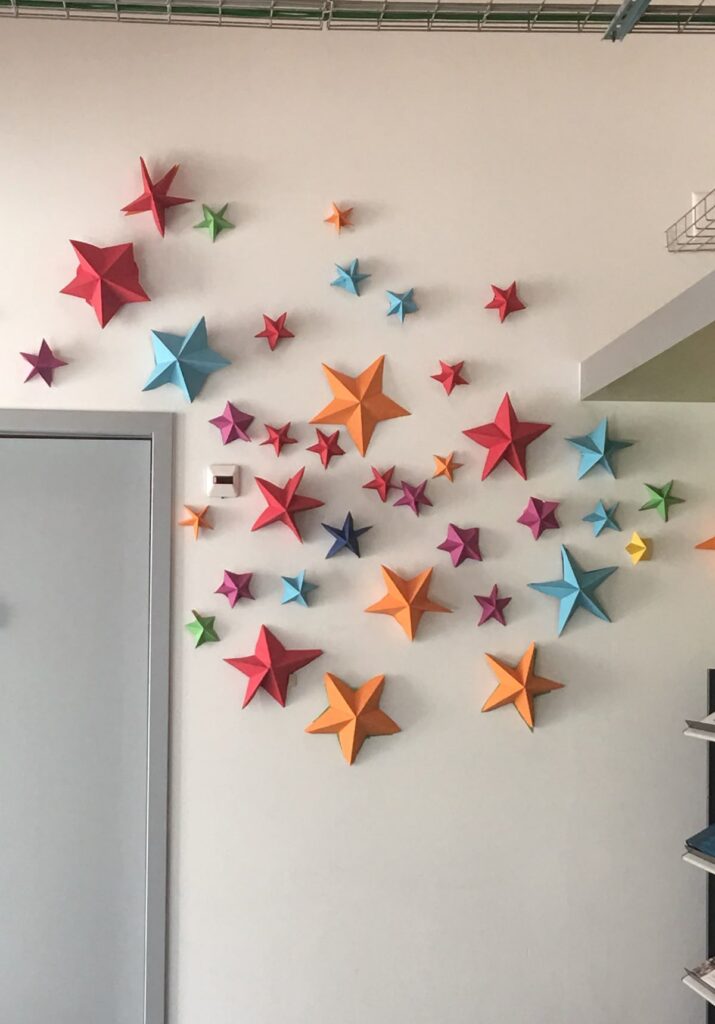 Colorful 3D star decorations on a white wall create a vibrant and artistic indoor display.