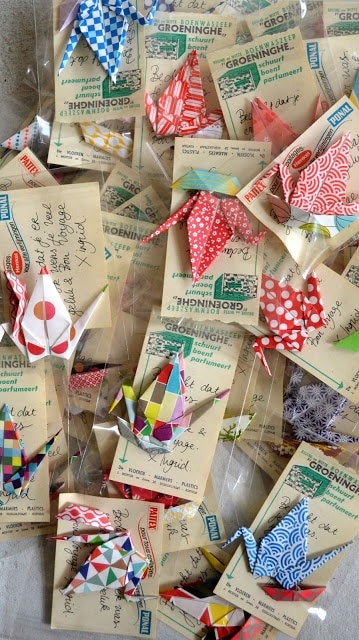 Colorful origami cranes arranged on vintage postcards, showcasing intricate patterns and artistic craftsmanship.