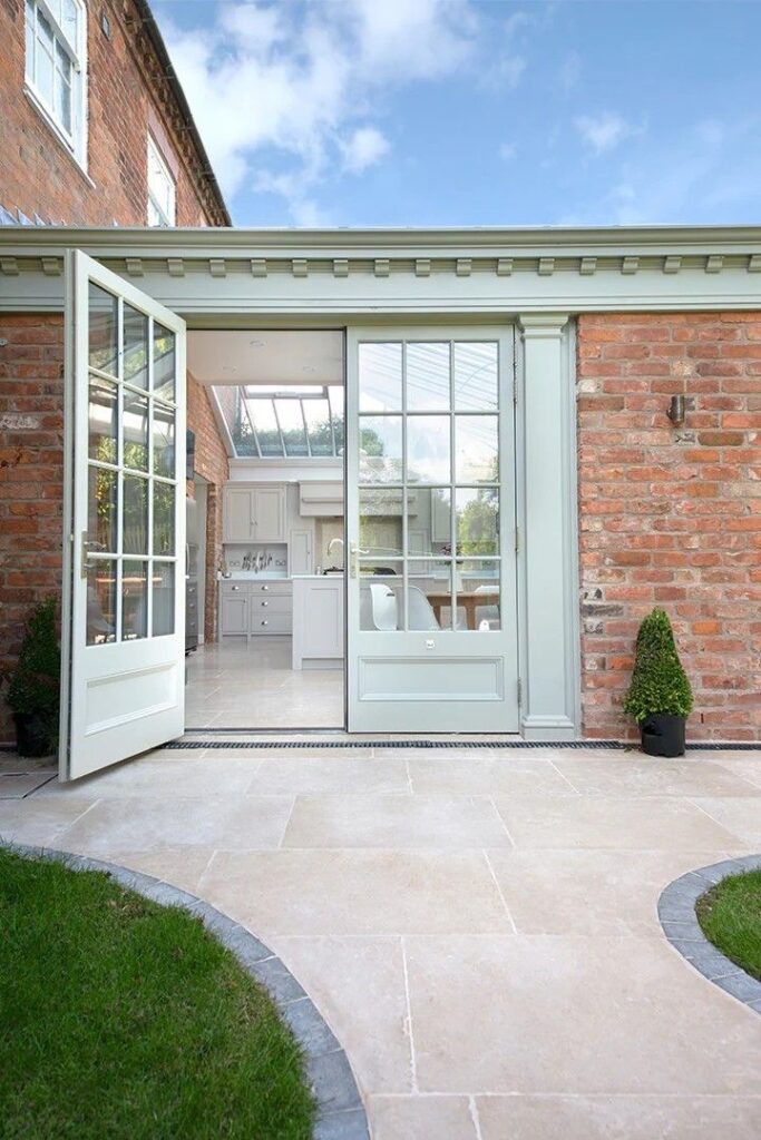 Modern kitchen extension with open glass doors and outdoor patio, blending brick and contemporary design.