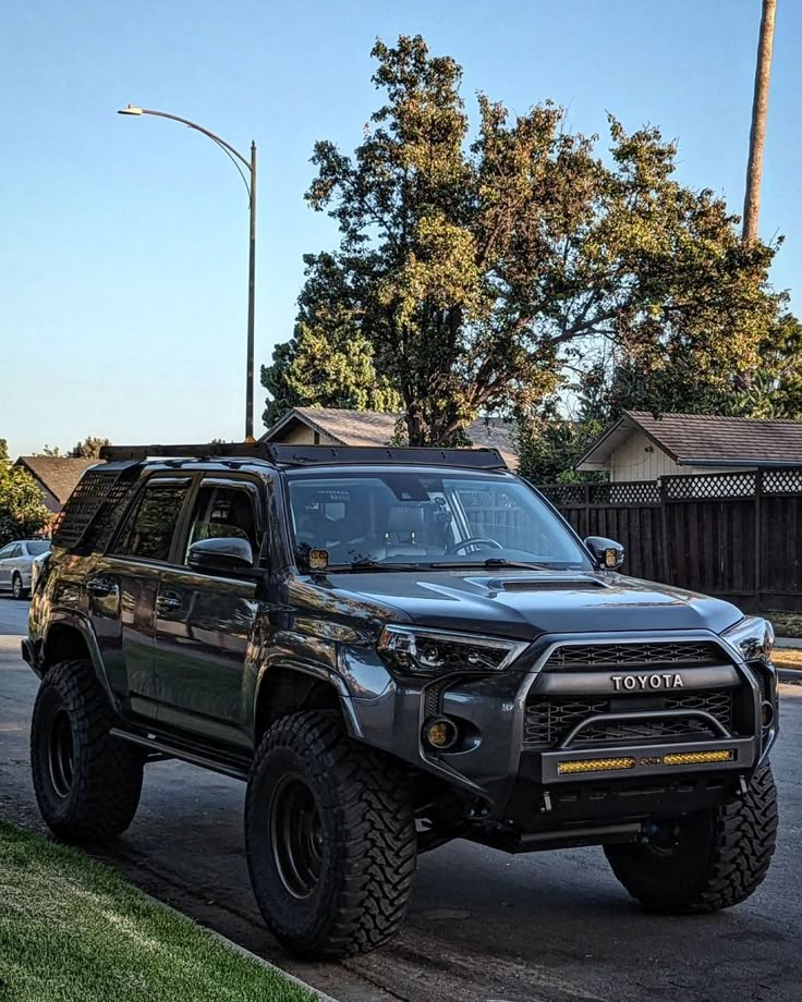ee49144d-273f-48bd-bac3-0e14dbd99ddb Lifted grey Toyota SUV parked on a suburban street, showcasing custom off-road tires and grille. | Sky Rye Design Lifted grey Toyota SUV parked on a suburban street, showcasing custom off-road tires and grille.
