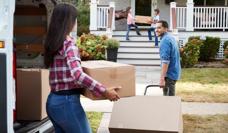 A family moving into a new home, unloading boxes from a van; teamwork and new beginnings concept.