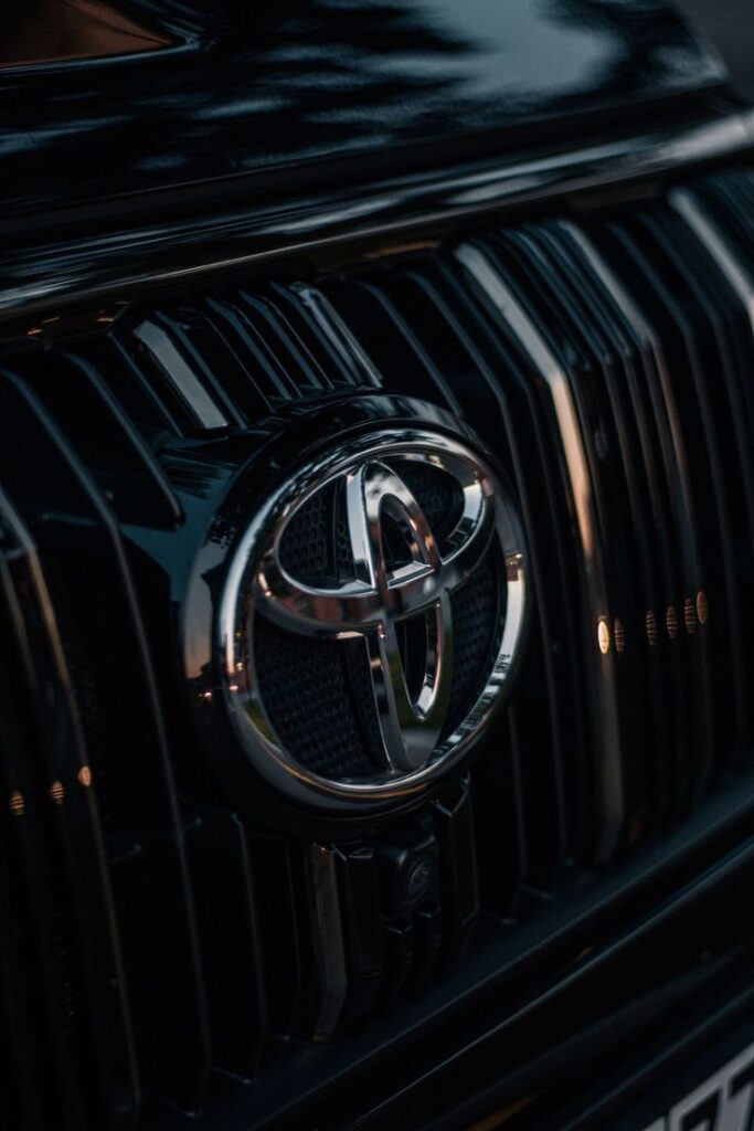 Close-up of Toyota grille and emblem on a black vehicle, showcasing sleek design and branding.