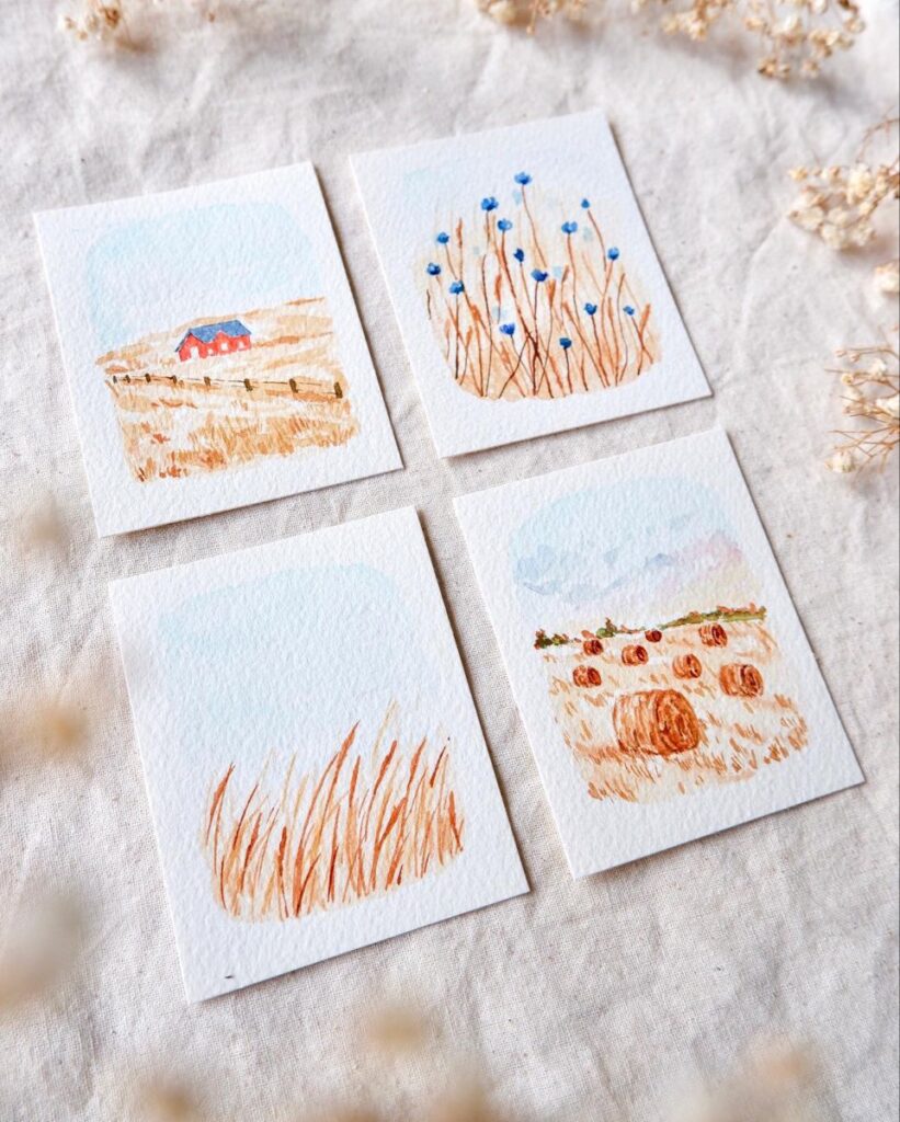 Four watercolor miniatures of landscapes: barn, blue flowers, tall grass, and hay bales on a textured surface.