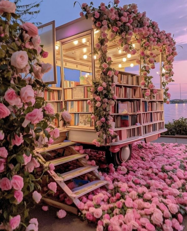 Mobile bookstore adorned with pink roses by a lakeside at sunset, creating an enchanting and romantic ambiance.