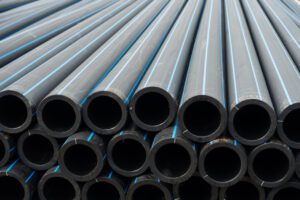 Black plastic pipes stacked, close-up view. Industrial construction materials arranged in a neat pile for efficient storage.