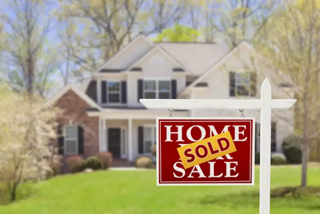 Sold home with a Home Sold sign in front of a two-story house and green lawn.