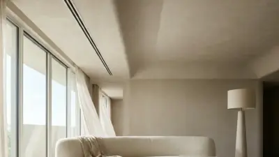 Modern minimalist neutral living room with curved sofa, floor-to-ceiling windows, sheer curtains and travertine coffee table.