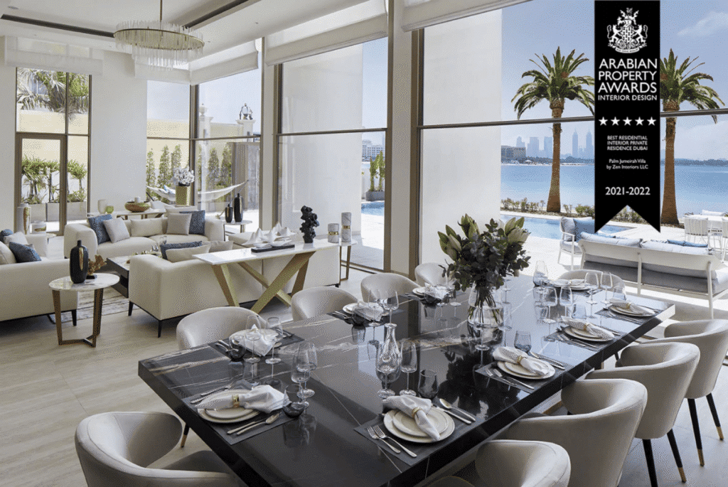 Luxurious dining area with sea view, elegant decor, and award banner for best residential interior design in Dubai.
