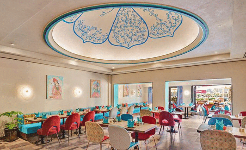 Colorful restaurant interior with elegant ceiling design, vibrant chairs, and artistic wall decor.