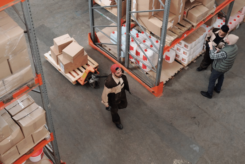 Warehouse workers organizing and discussing inventory in an industrial storage facility, featuring boxes and containers.