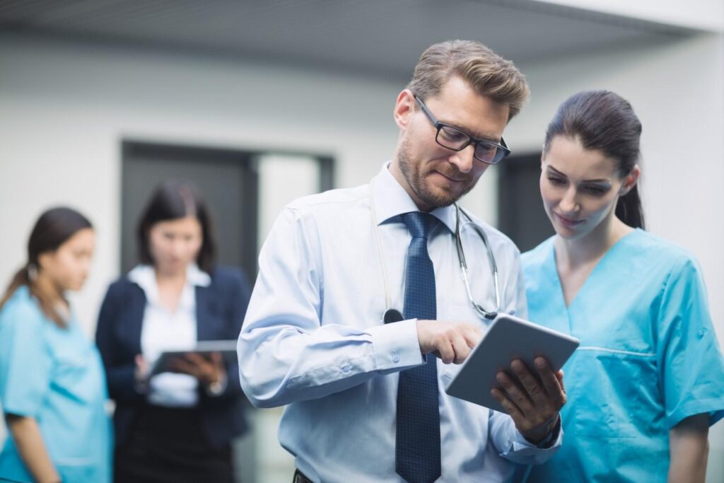 Doctor and nurse reviewing medical data on a tablet in a hospital setting.
