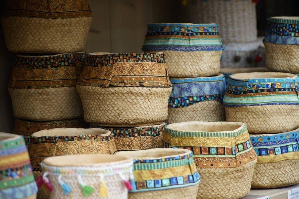 Colorful woven baskets with patterned fabric rims stacked on display at a market.