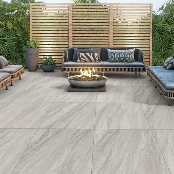 Modern outdoor patio with gray stone tiles, stylish seating, and a central fire pit for a cozy ambiance.
