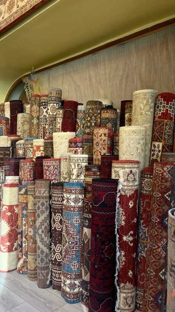 persian rugs Rolled-up colorful oriental rugs displayed in a store, showcasing intricate patterns and designs. | Sky Rye Design Rolled-up colorful oriental rugs displayed in a store, showcasing intricate patterns and designs.