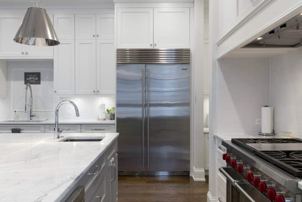 Modern kitchen with stainless steel fridge, marble countertop, and gas stove.