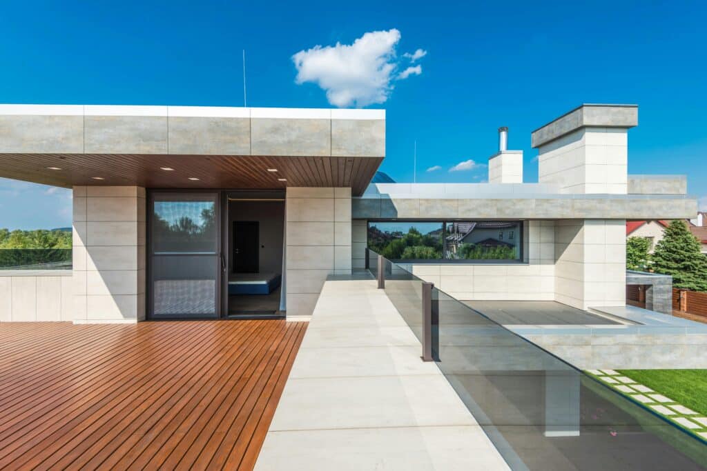 Modern home with spacious rooftop terrace featuring wood flooring and clear blue sky background.