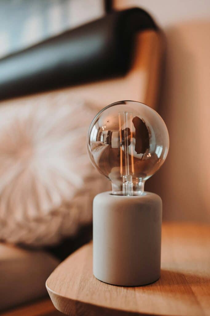 Modern decorative lamp on a wooden table in cozy living room setting.