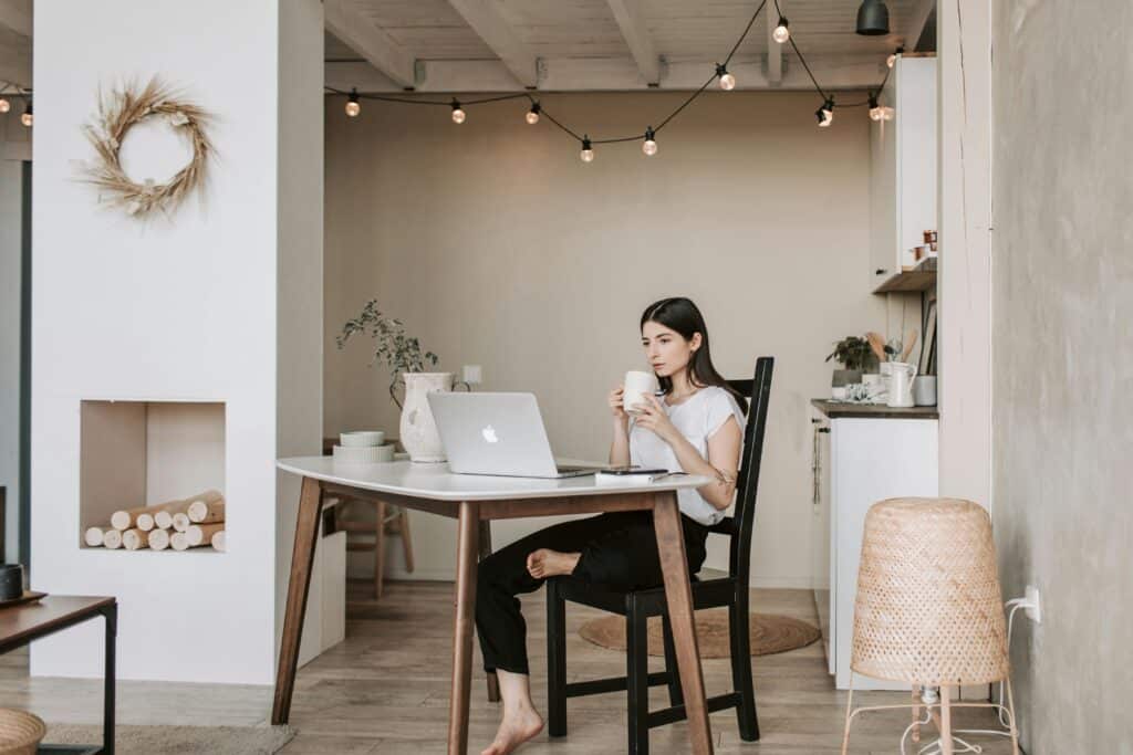 pexels-vlada-karpovich-4050314 Woman working on laptop in cozy home kitchen, drinking coffee, with warm lighting and minimal decor. | Sky Rye Design Woman working on laptop in cozy home kitchen, drinking coffee, with warm lighting and minimal decor.