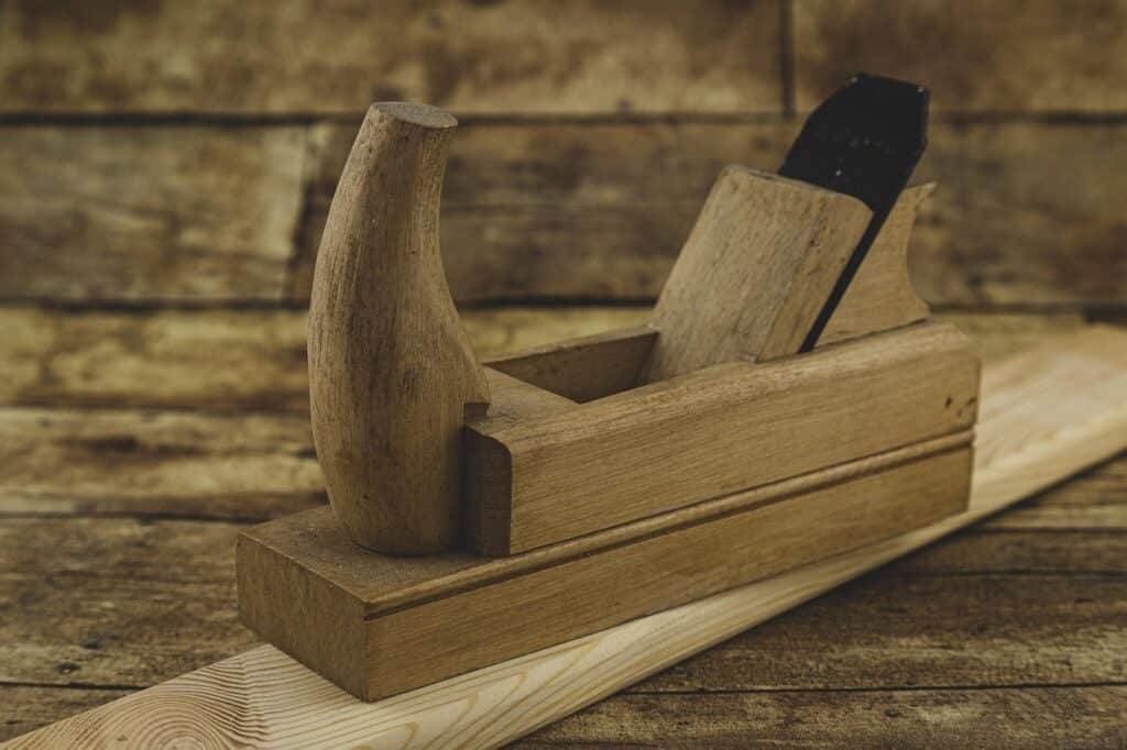 Vintage wooden hand planer on a rustic wooden surface, ideal for woodworking projects.