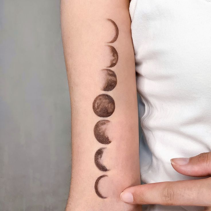 Tattoo of moon phases on an arm, showcasing lunar cycle artistry on skin.