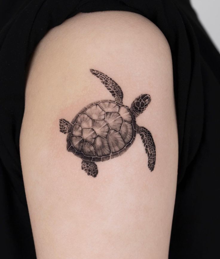 Realistic turtle tattoo on upper arm, showcasing intricate details and black ink artistry.