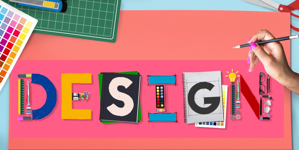 Creative design concept with colorful stationery forming the word 'DESIGN' on a vibrant pink surface.