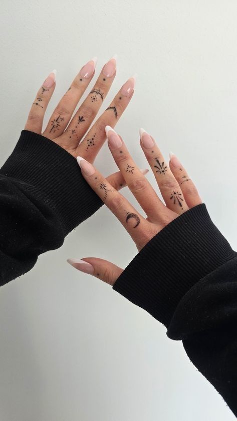 _ Hands with minimalist black finger tattoos and long nude nails, wearing a black sweater against a white background. | Sky Rye Design Hands with minimalist black finger tattoos and long nude nails, wearing a black sweater against a white background.