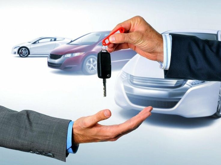 Handing over car keys in front of three cars, symbolizing a successful car purchase or rental agreement.