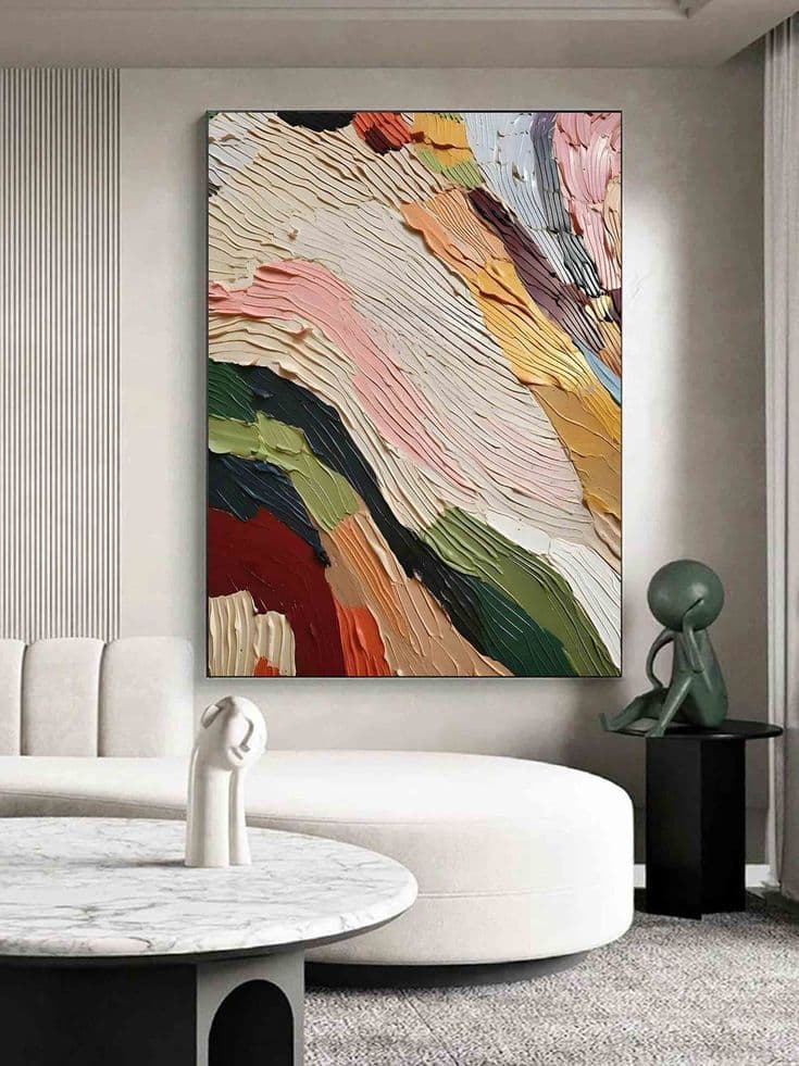 Abstract textured painting with multicolor strokes in a modern living room, featuring a white sofa and round table.