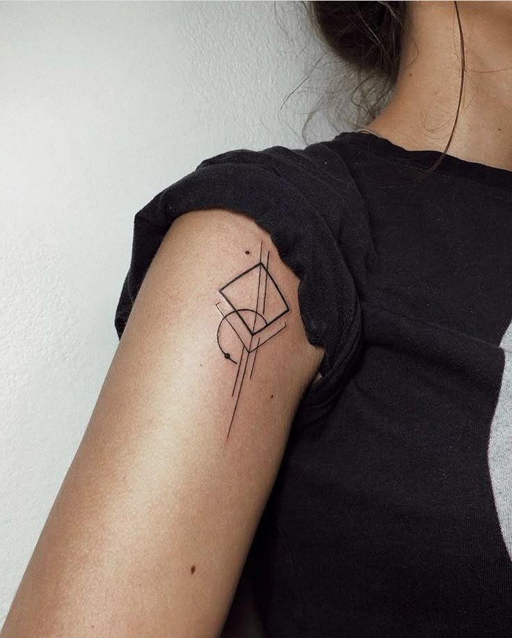 Женское тату Abstract geometric tattoo on upper arm, featuring intersecting lines and shapes, minimalist design. | Sky Rye Design Abstract geometric tattoo on upper arm, featuring intersecting lines and shapes, minimalist design.