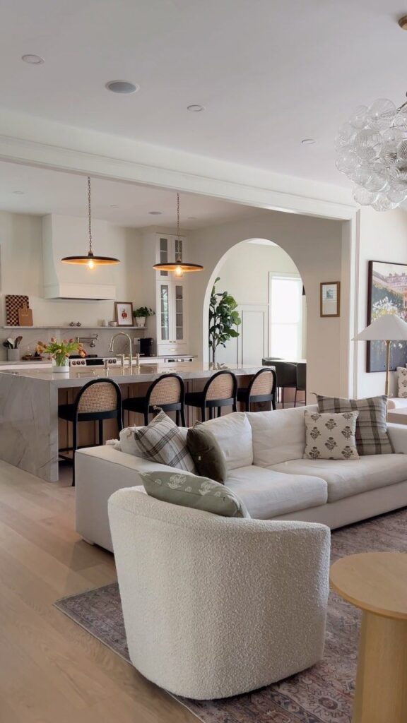 Modern open-plan living room with cozy seating, stylish kitchen island, and chic lighting.