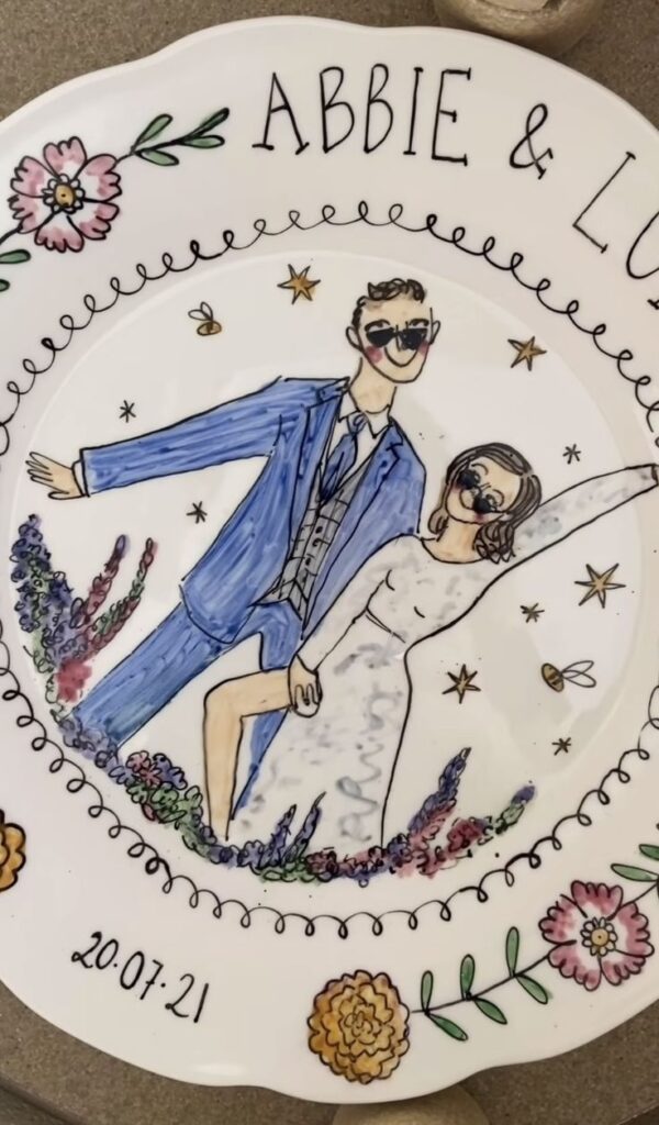 Hand-painted wedding plate with illustrated couple, floral border, and date 20.07.21.