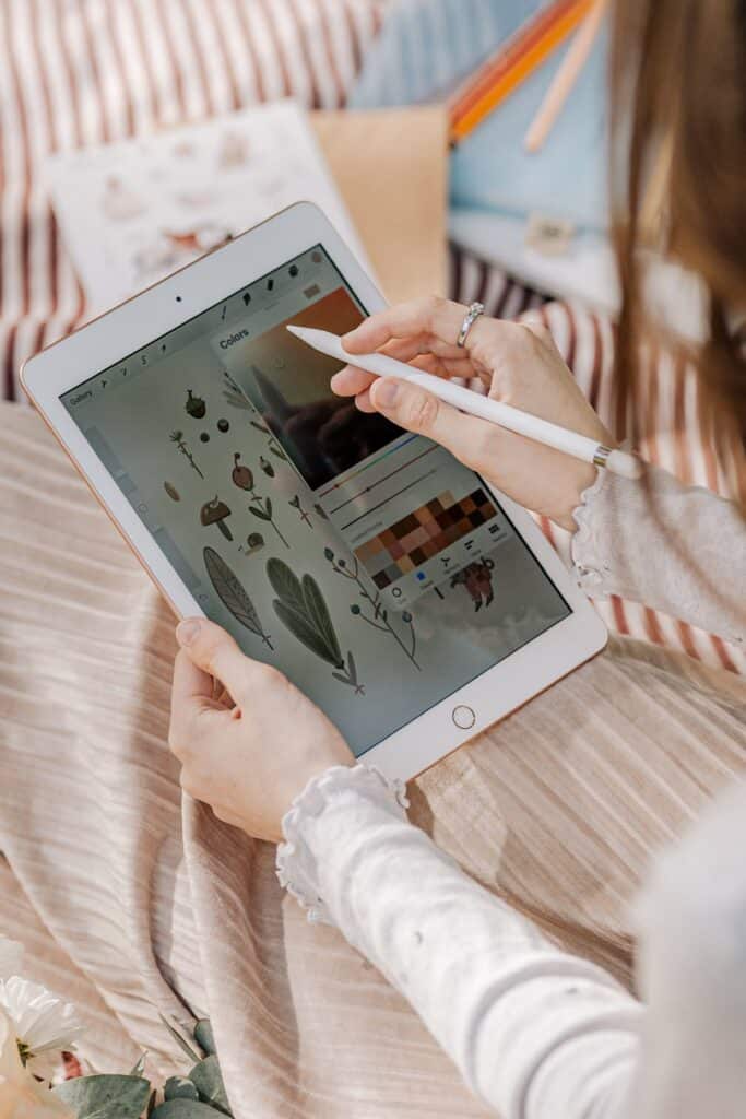 Person drawing plant illustrations on a tablet with a stylus, enhancing digital creativity and design skills.