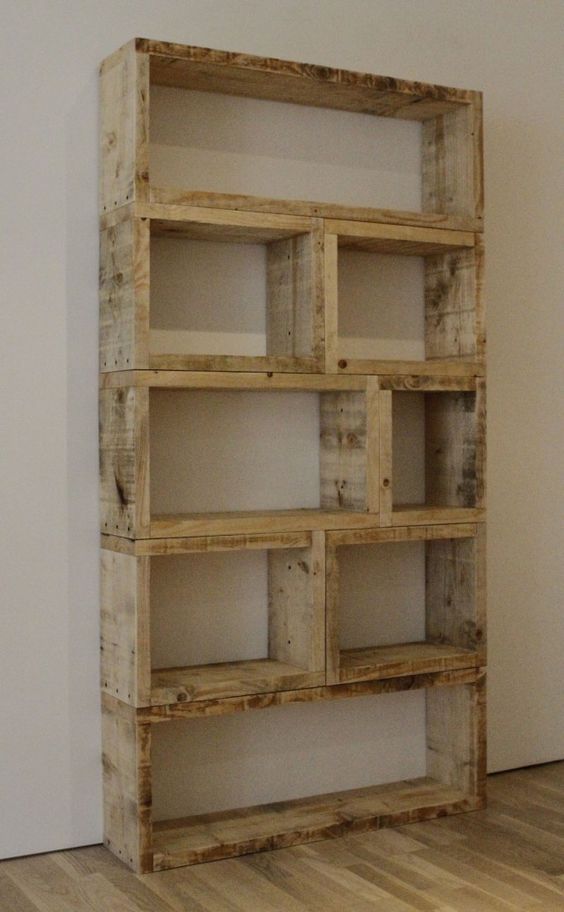 Wooden shelf unit made from natural wood, featuring multiple rectangular compartments, against a neutral wall.