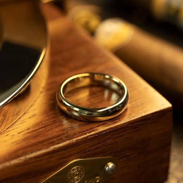 Elegant gold ring on a polished wooden box background, showcasing luxury and sophistication.