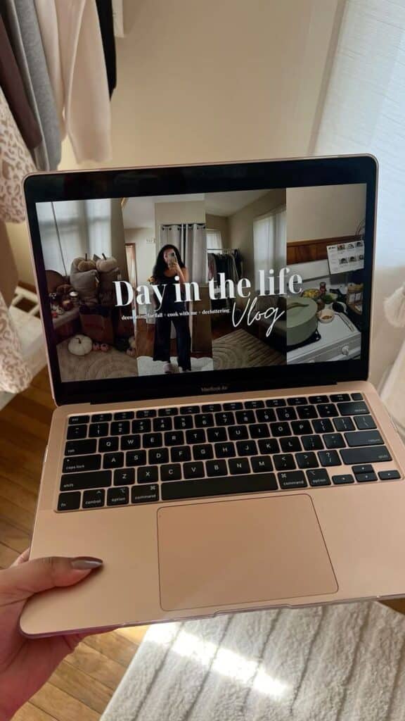 Laptop showing Day in the life vlog title, fall decor, cooking, and decluttering in a cozy room setting.
