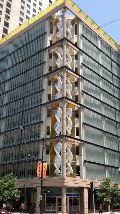 Modern urban building with unique spiral staircases on its facade, seen on a sunny day.