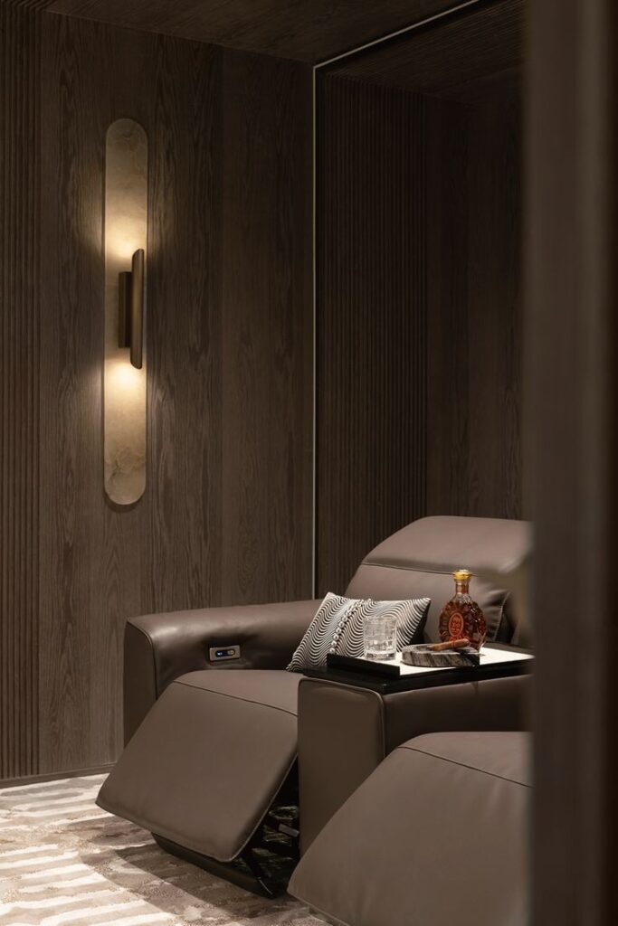Luxurious home theater with leather recliners, a stylish wall light, and a side table with decor accents.