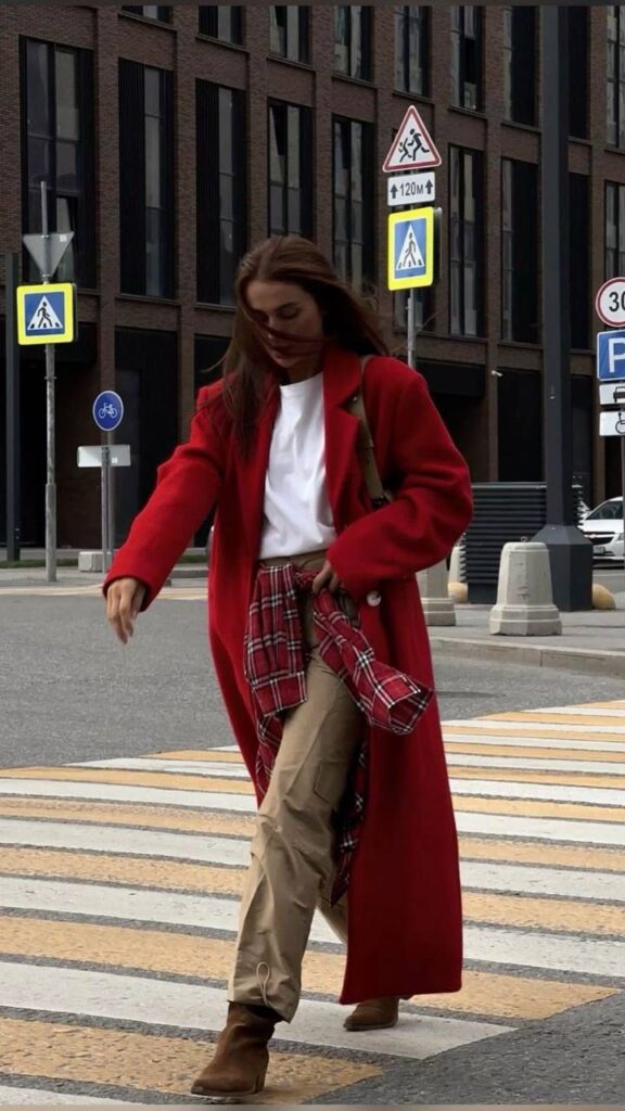 Woman in a red coat walking across a city street crosswalk, urban style fashion.
