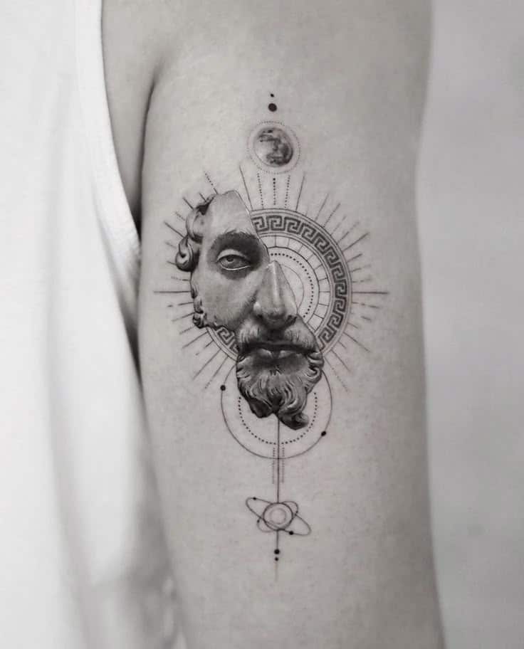 Tattoo of an ancient sculpture face with geometric and celestial designs on an arm.