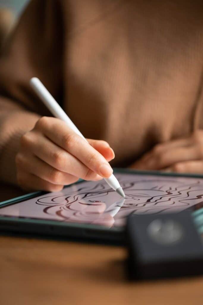 Person drawing on a tablet with a stylus, creating a detailed digital art piece.
