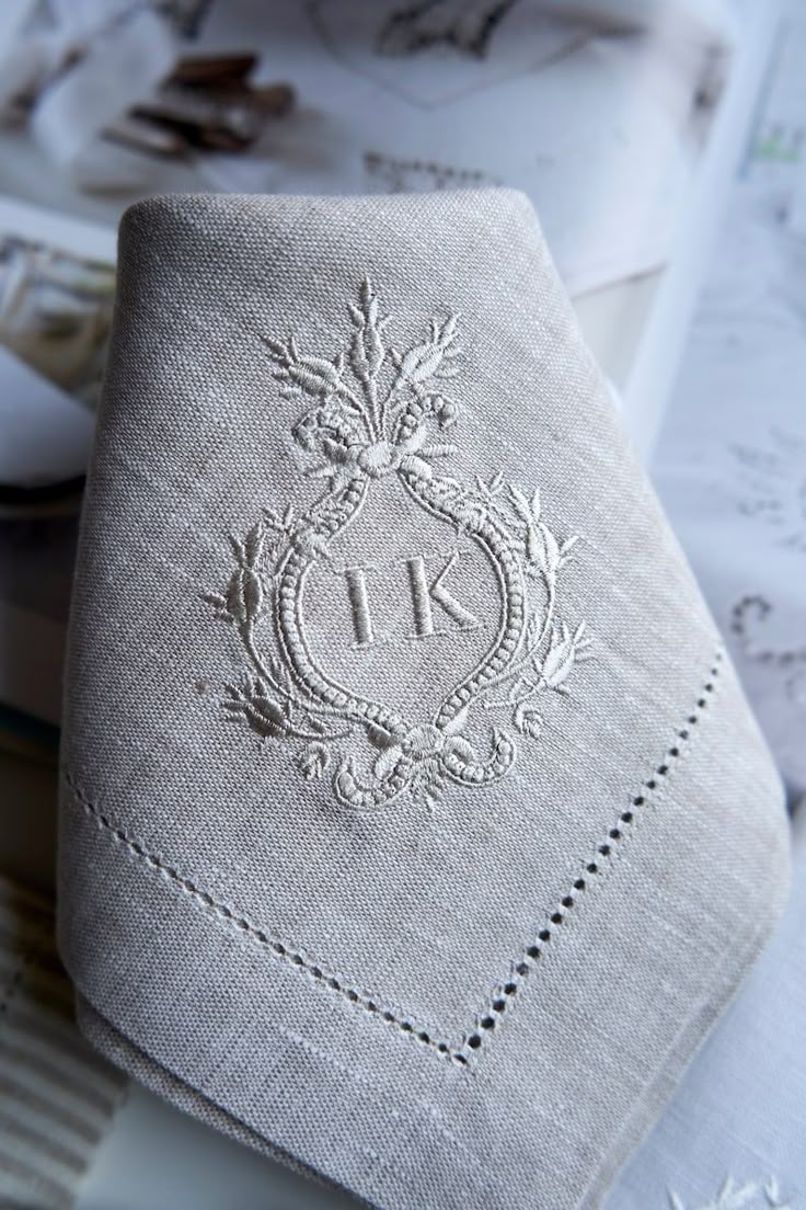 Elegant linen napkin with decorative embroidery and initials IK, perfect for upscale dining or weddings.