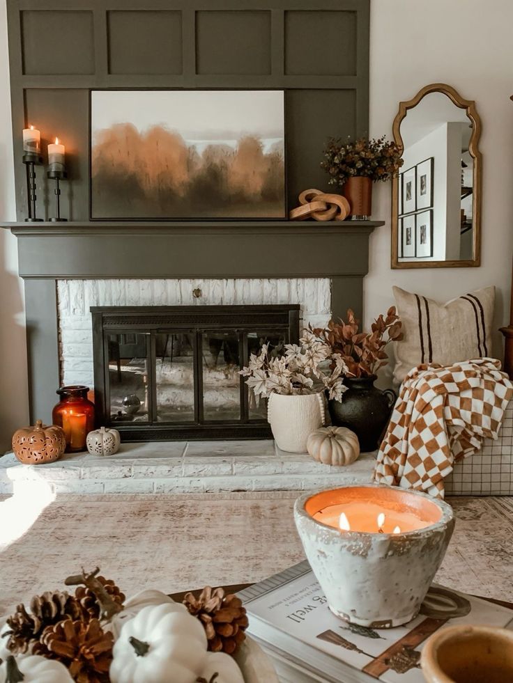 Cozy autumn fireplace decor with candles, pumpkins, and a checkered blanket, creating a warm, inviting atmosphere.